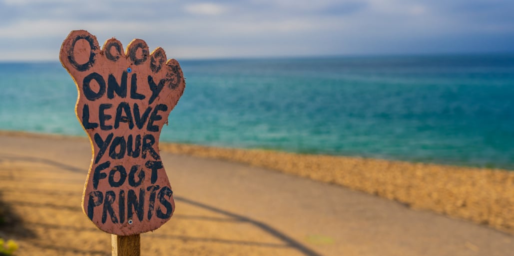 Skilt langs en vei ved stranden med teksten Only leave your footprints